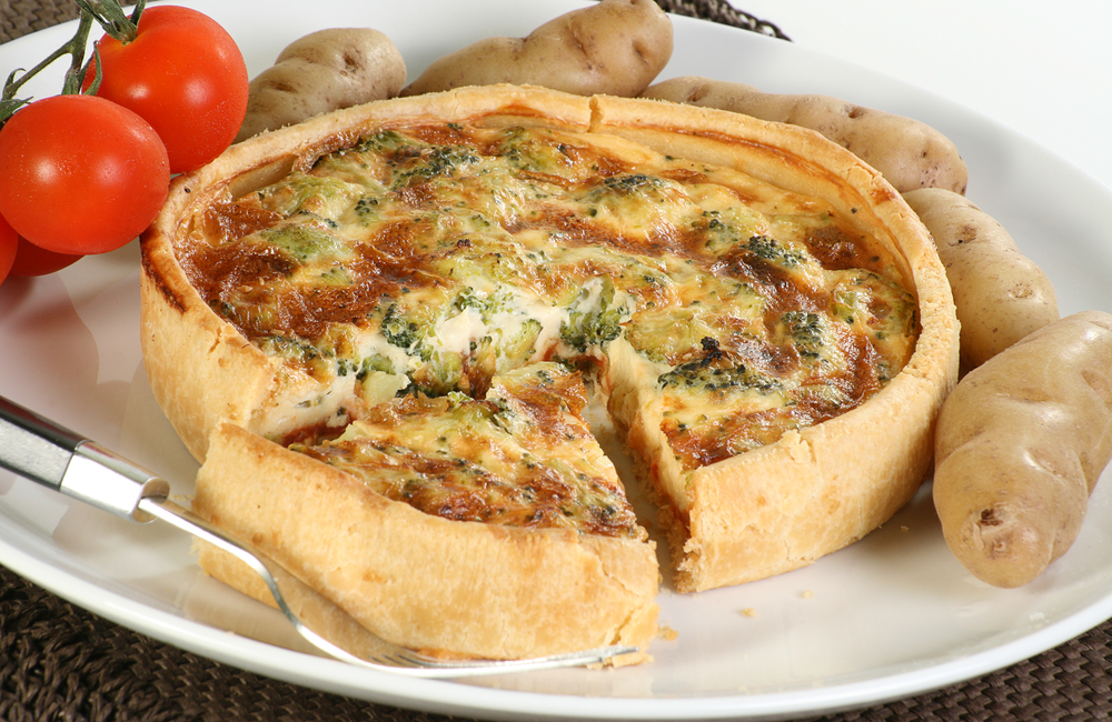 Golden broccoli quiche with a slice ready to serve
